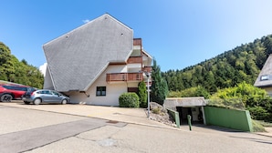 Ein Gebäude mit einem geneigten Dach, einem Balkon und einem kleinen Anbau.