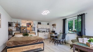 Ein modernes Schlafzimmer mit Bett, Essbereich und Küche.