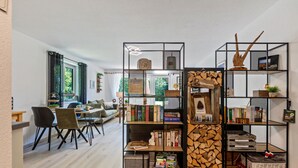 Ein modernes Wohnzimmer mit Essbereich, Bücherregal und Kamin.
