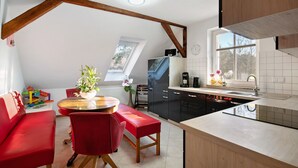Una cocina moderna con comedor, vigas de madera, una ventana y un sofá rojo.