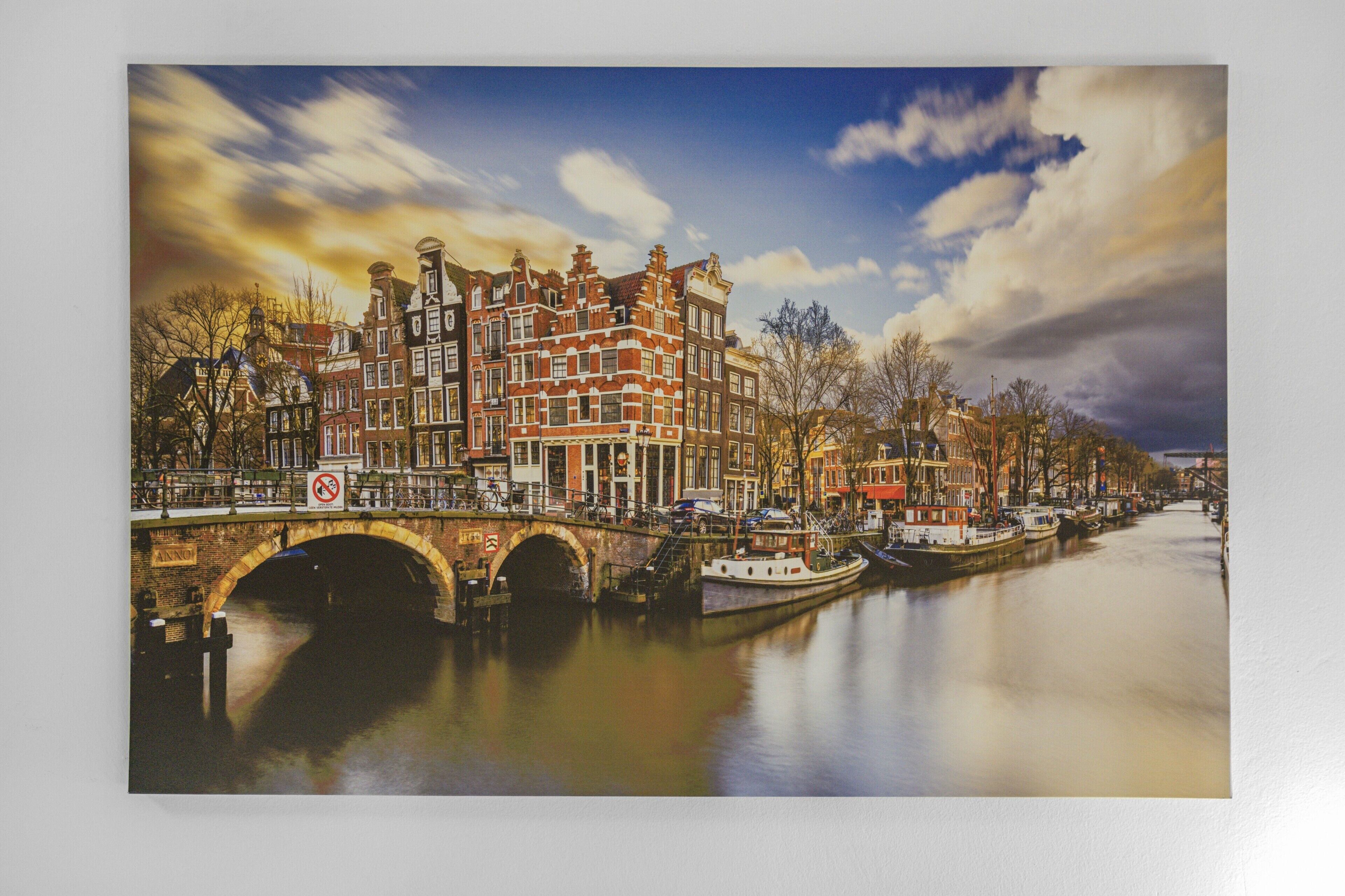 A canal with buildings on one side and a bridge in the foreground.