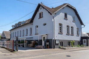 Un bâtiment à deux étages, doté d’un toit à pignon, d’une entrée couverte et d’un petit jardin.