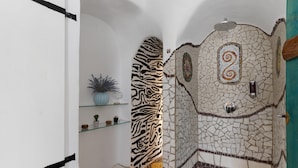 Een badkamer met een mozaïekwand, een accentmuur met zebrapatroon, en een plank met decoratieve objecten.