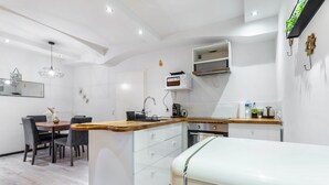 Una cocina moderna con armarios blancos, encimera de madera y un comedor con mesa y sillas.
