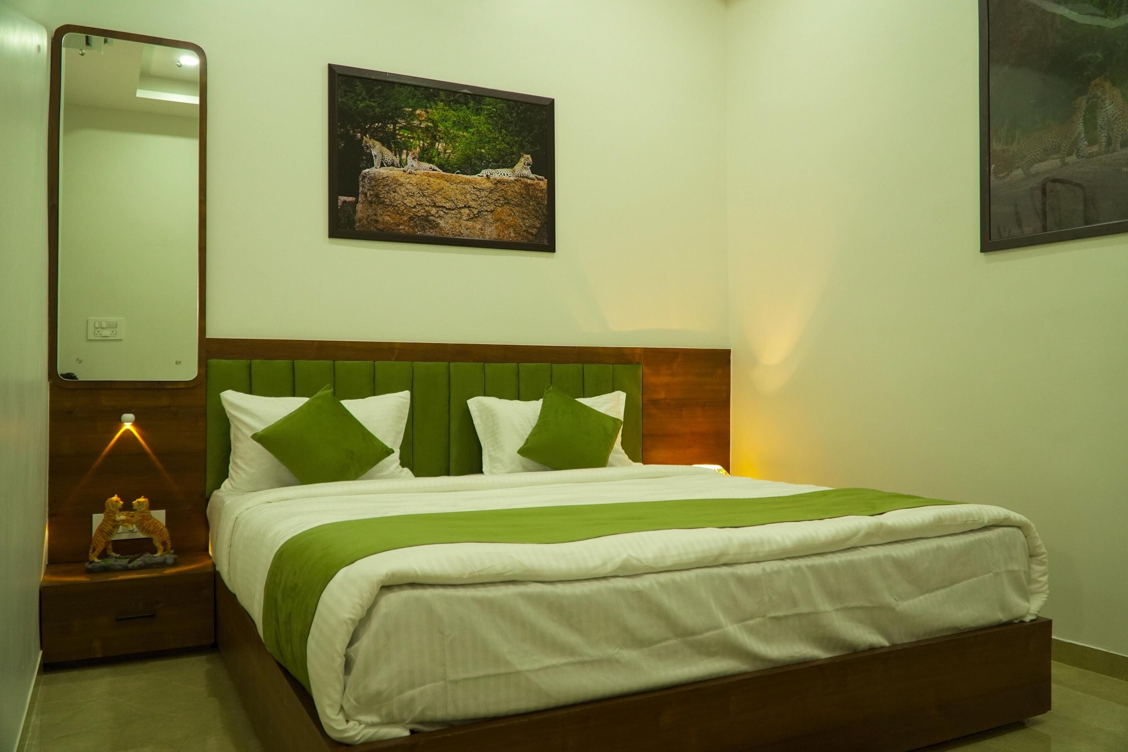A neatly made bed with green and white bedding, a wooden headboard, and a nightstand with a lamp and a small figurine.