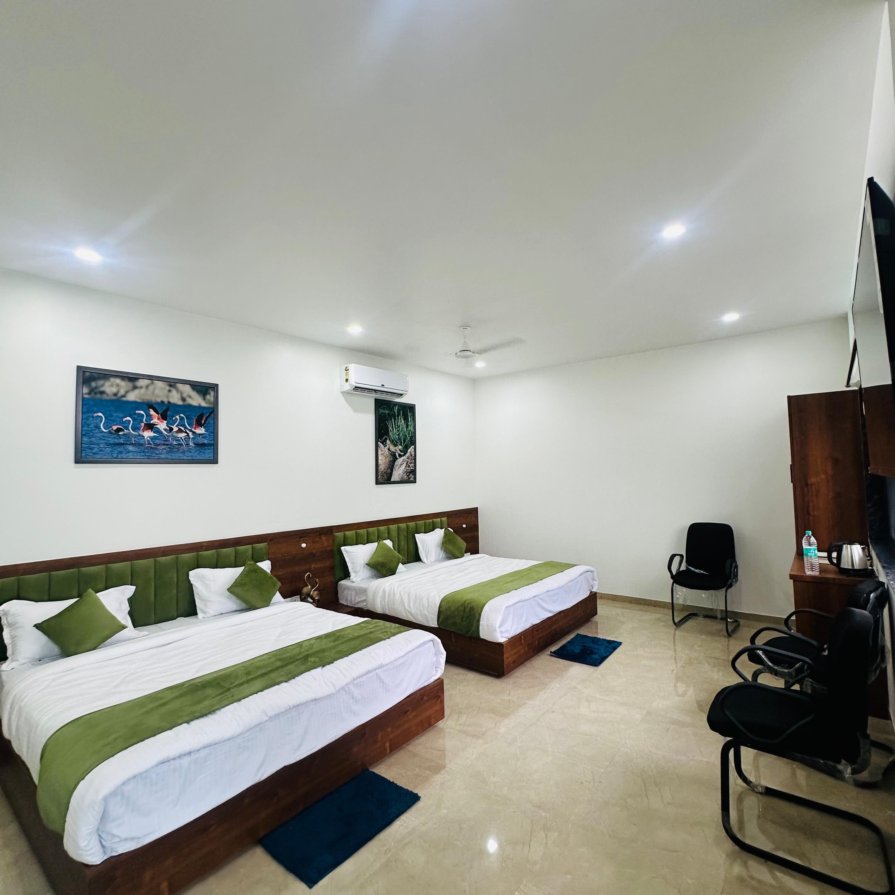 A hotel room with two beds, a TV, a desk, and a chair.