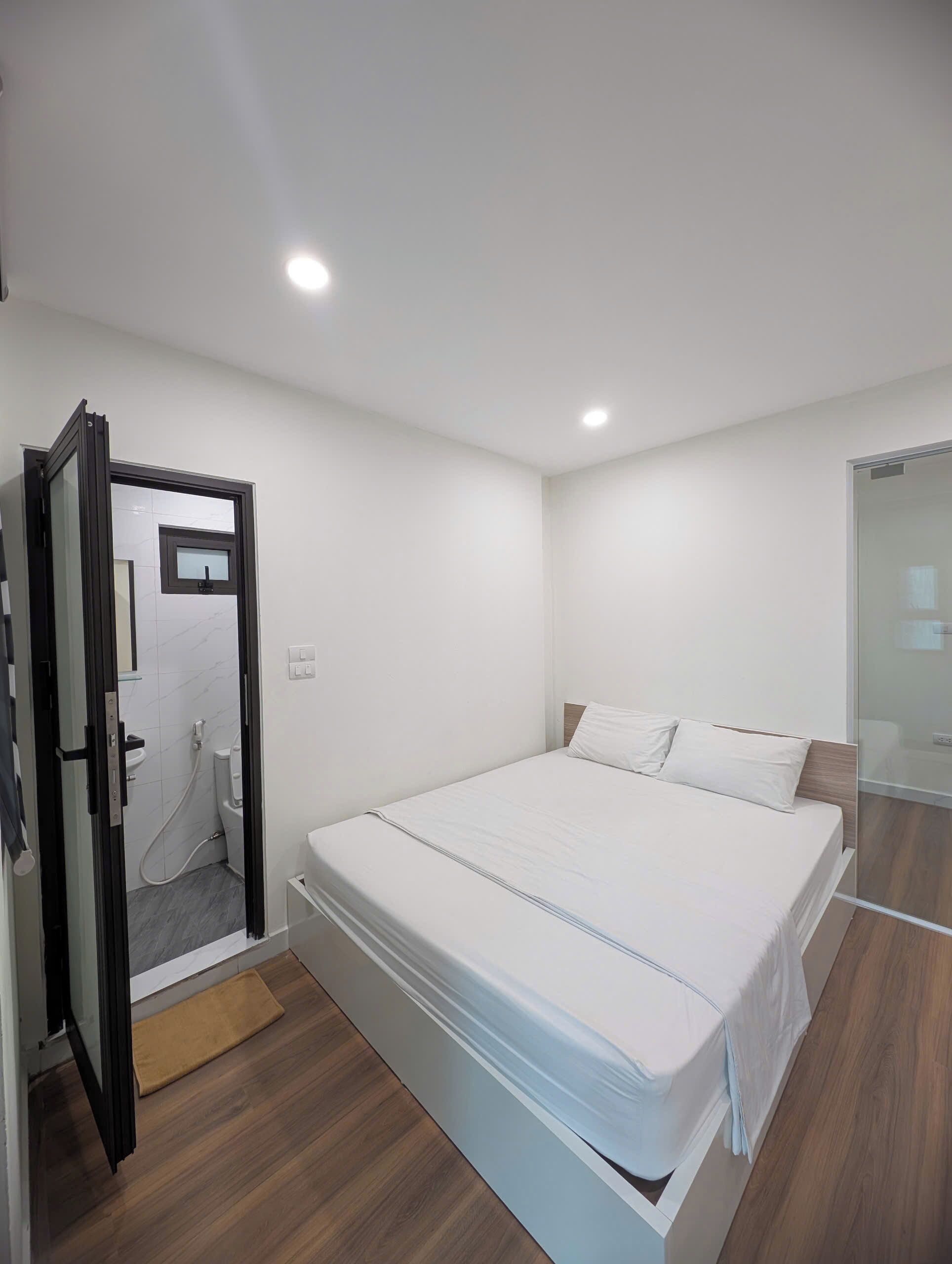 A modern bedroom with a bed, a shower area, and a glass door leading to a bathroom.