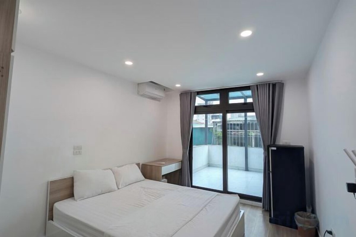 Une chambre avec un lit, un bureau, une télévision et un balcon offrant une vue.