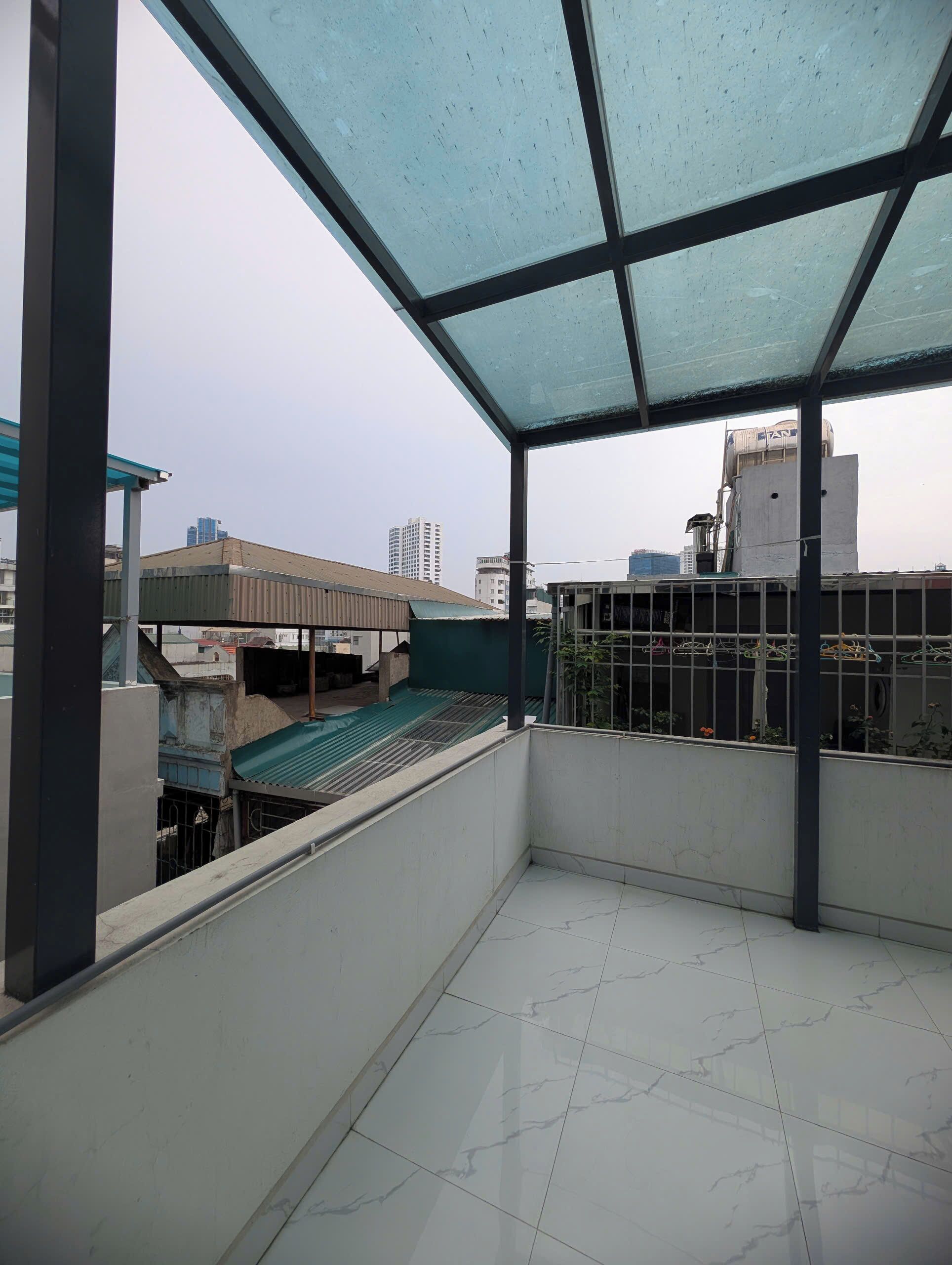 A balcony with a view of a cityscape, including buildings and a water tower.