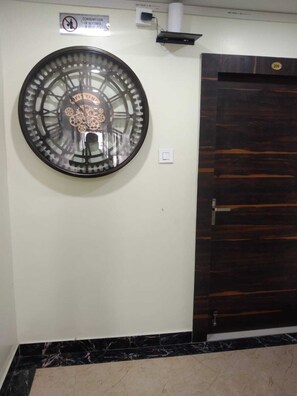 A wall-mounted clock with Roman numerals and a decorative center, a wooden door with a number plate, and a sign prohibiting alcohol consumption. - N.s Hotel Banquet & Cafe  By GRB (Danapur)