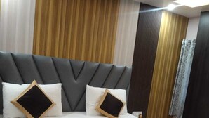 Ein modernes Hotelzimmer mit einem großen Bett, einem Holzkopfschild und einer neutralen Farbgestaltung.