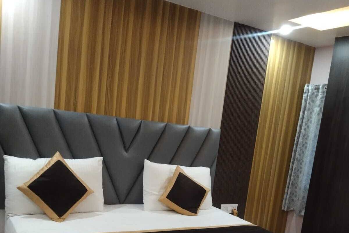 Une chambre d’hôtel moderne avec un grand lit, une tête de lit en bois et une palette de couleurs neutres.