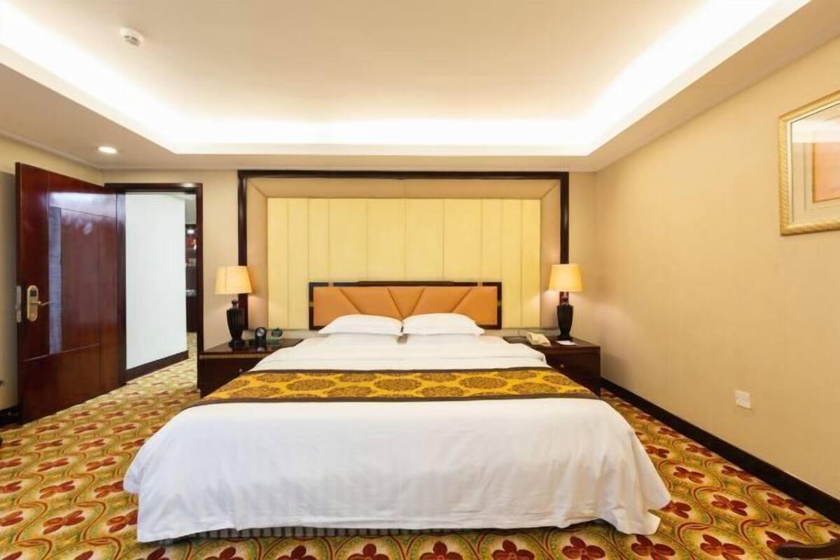 Une chambre d’hôtel avec un grand lit, deux tables de chevet et une porte.