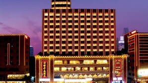 Um hotel com vários andares, átrio central iluminado e entrada destacada.