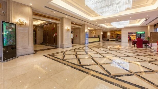 Um hall amplo com piso de mármore, um lustre e um balcão de recepção.