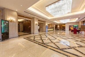 A spacious lobby with a marble floor, a chandelier, and a reception desk. - Huayuan Hotel (Guangzhou)