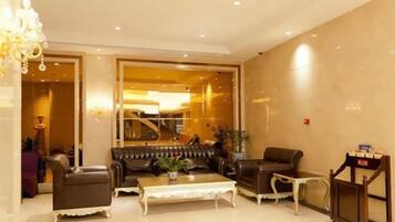 A hotel lobby with a sofa set, a coffee table, and a reception desk.