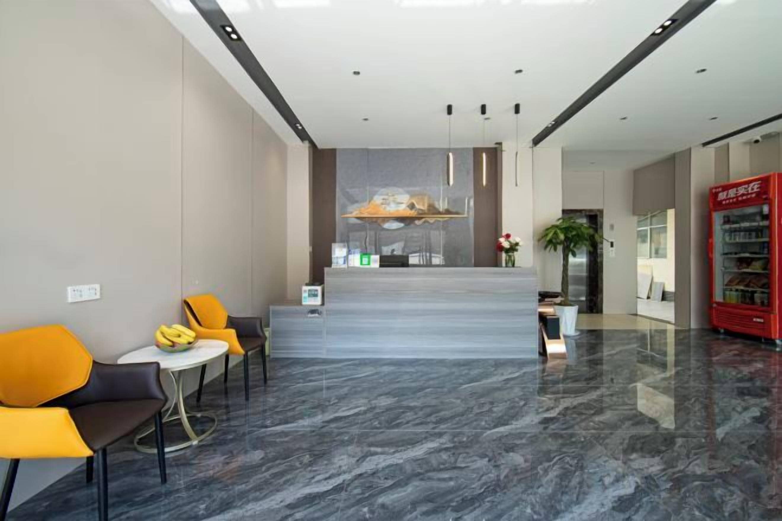A hotel lobby with a reception desk, seating area, and vending machine.
