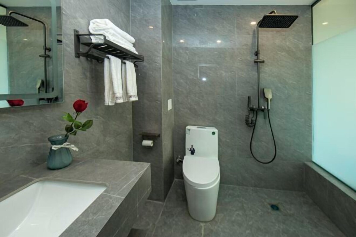 Un baño moderno con un espejo grande, un lavamanos blanco, inodoro y ducha.
