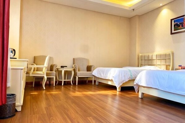 A hotel room with two beds, a desk, and two chairs.