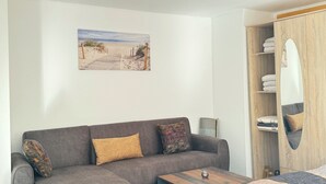 Et moderne værelse med en grå sofa, et træbord og et maleri med et strandmotiv på væggen.