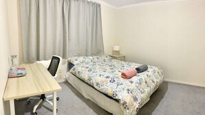 Un dormitorio pequeño y ordenado con una cama individual, un escritorio y una silla.
