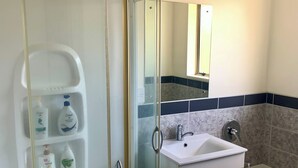 Un baño con ducha acristalada, lavabo blanco y bañera.