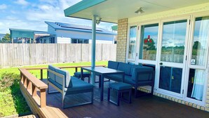Un patio techado con una mesa y sillas, un banco de madera y vistas a una casa vecina.