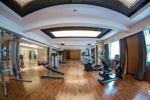 A gym with exercise equipment, a wooden floor, and a large window. - Licheng Youde Hotel (Putian)