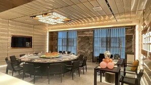 A modern dining area with a round table set for a meal, a smaller table with balloons, and a stone wall backdrop. - Licheng Youde Hotel (Putian)