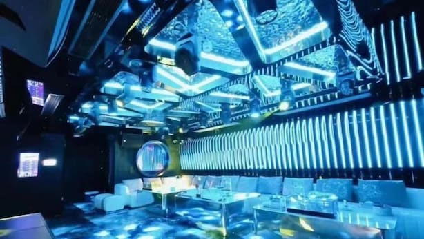 A room with a futuristic design, featuring a ceiling with geometric patterns and a floor with a reflective surface. - Licheng Youde Hotel (Putian)