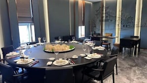 A conference room with a round table set for a meeting, equipped with chairs, plates, cutlery, and glasses. - Licheng Youde Hotel (Putian)