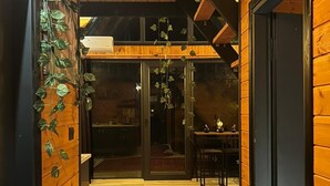 A wooden interior with a red patterned rug, a dining area with a table and chairs, and a staircase leading to an upper level. - MİRA BUNGALOV (Trabzon)