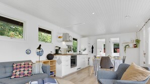 Ett modernt, öppet vardagsrum med kök, matplats och sittgrupp.