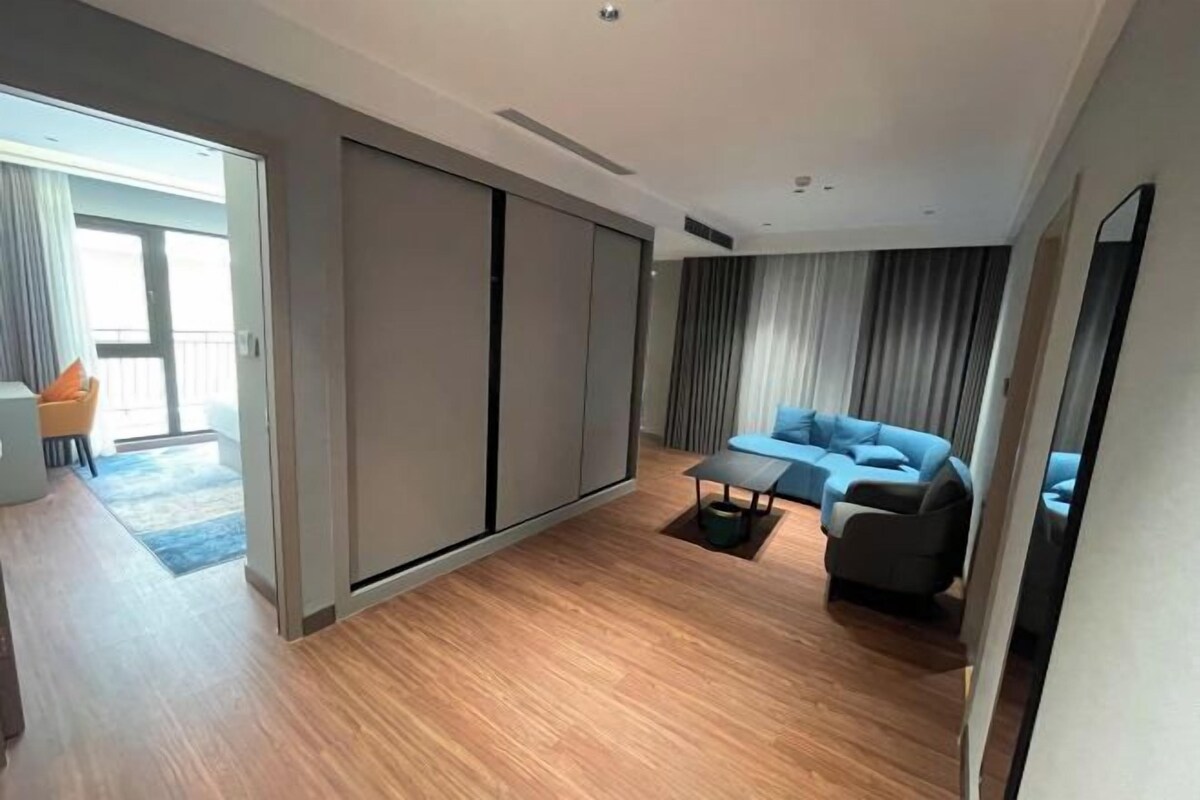 A modern living room with a sofa, a coffee table, and a sliding door leading to a balcony.