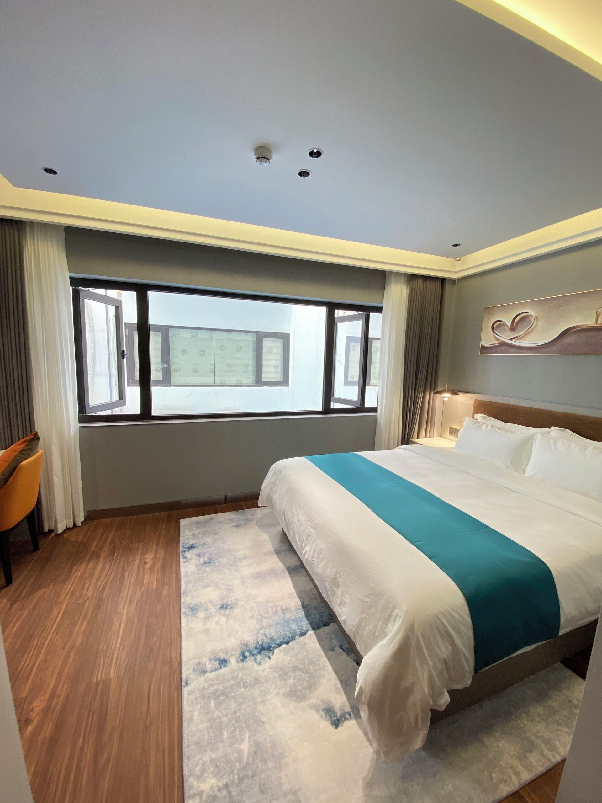 Une chambre d’hôtel moderne avec un grand lit, une vue sur la ville et un plancher en bois.