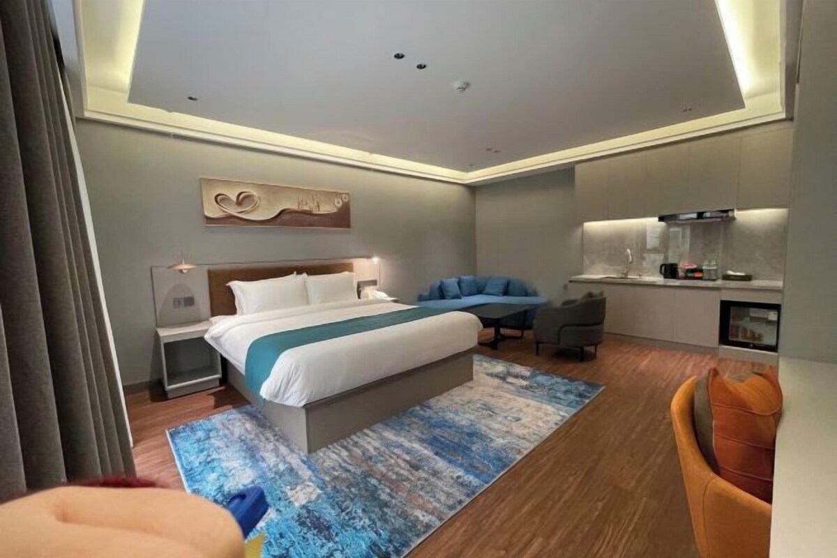 A modern hotel room with a large bed, a desk, and a seating area.