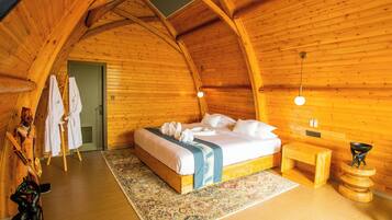 A cozy, wooden cabin room with a bed, bedside table, and a small wooden stool.