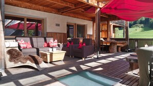 Une terrasse en bois avec une piscine, des chaises longues et une table.