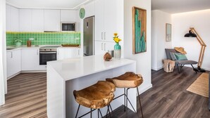 Eine moderne Küche mit weißen Schränken, einer grünen Spritzschutzwand und einer zentralen Kochinsel mit Sitzgelegenheiten.