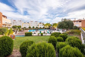 Un quartier résidentiel doté d’une piscine, de chaises longues et d’arbustes soigneusement taillés.