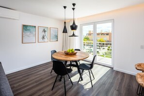 Un espace repas avec une table ronde en bois, des chaises noires et des luminaires suspendus.