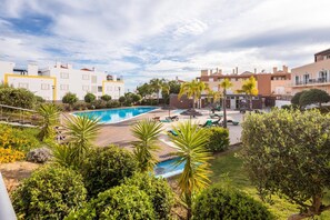 Un quartier résidentiel doté d’une piscine, de chaises longues et de palmiers.