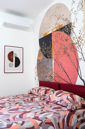 Une chambre à coucher avec un lit, une grande peinture abstraite et une œuvre d’art encadrée accrochée au mur.