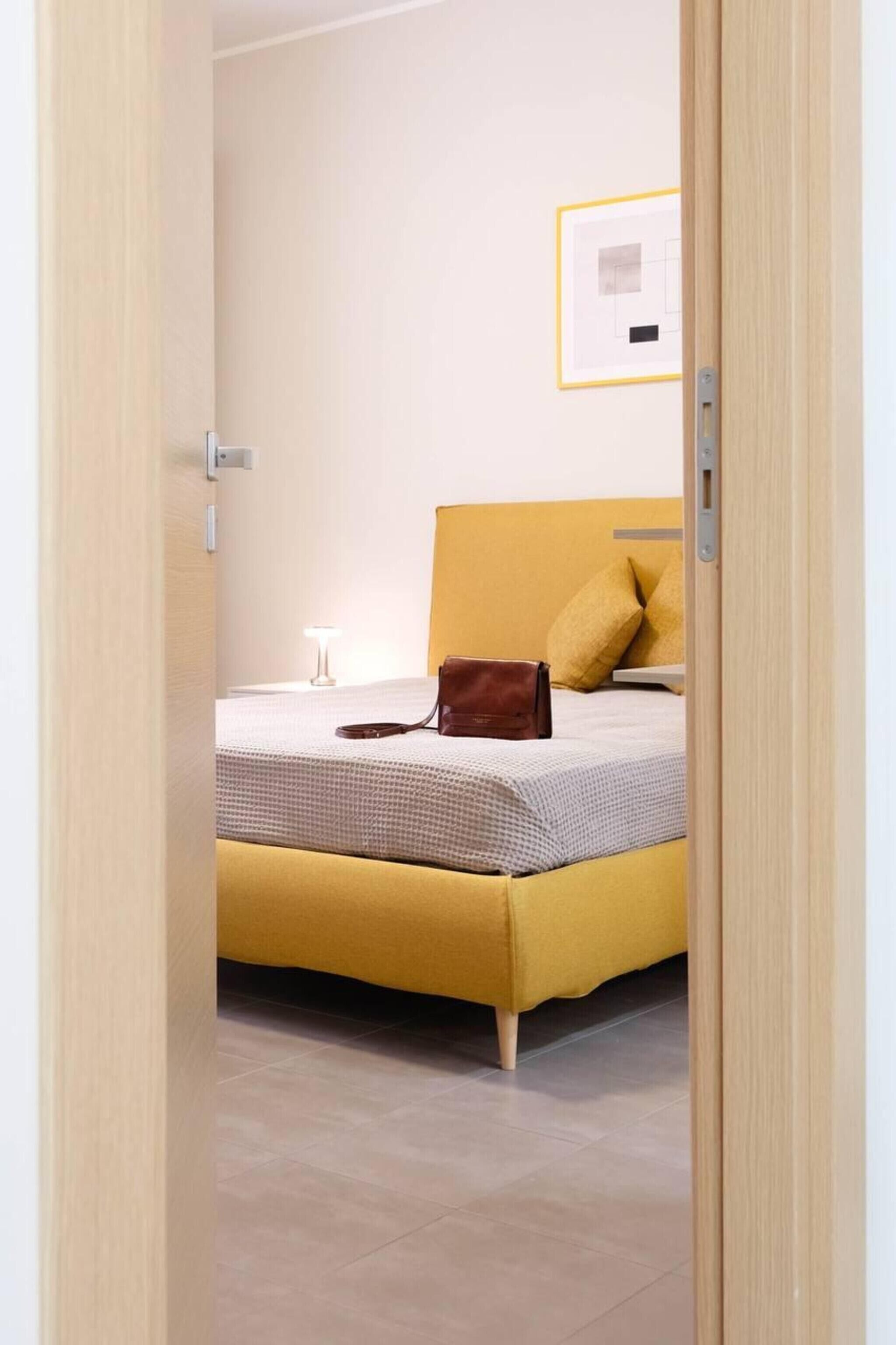 Una habitación con cama, lámpara de noche y un cuadro en la pared.