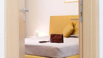 Una habitación con cama, lámpara de noche y un cuadro en la pared.