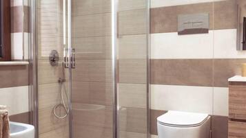 A modern bathroom with a glass-enclosed shower, a white toilet, and a wooden vanity.