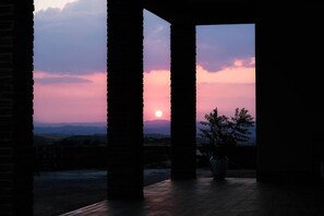 A sunset view through a doorway with columns, a potted plant, and a distant landscape. - Room 'Stanza Del Grano' with Shared Terrace, Wi-Fi and Air Conditioning (Mazzarino)