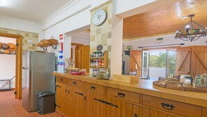 Eine Küche mit Holzausstattung, einem Edelstahlkühlschrank, einer Uhr und einer Kronleuchter.