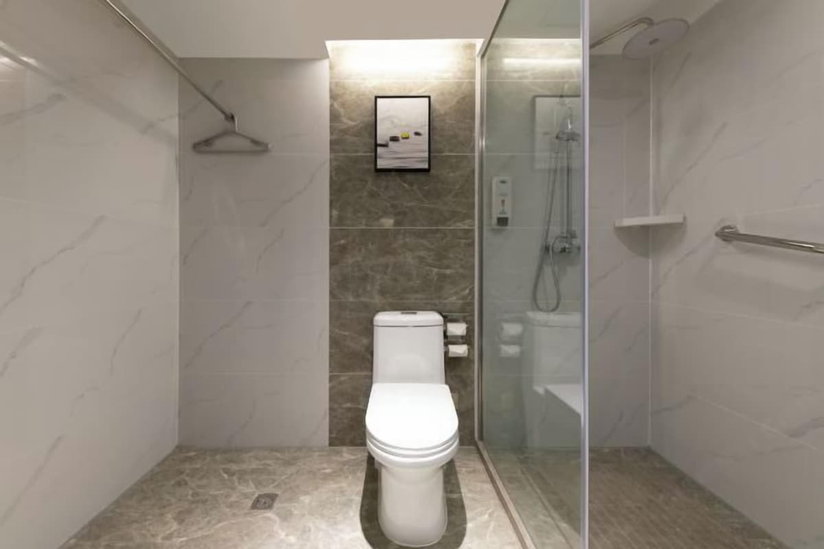 A modern bathroom with a toilet, a shower enclosure, and a marble wall.